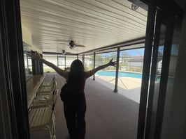 Woman walking onto a patio with arms outstretched.